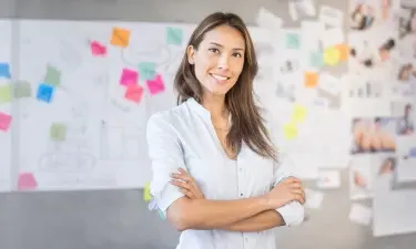 Smiling marketing professional standing in front of creative project board with colorful sticky notes